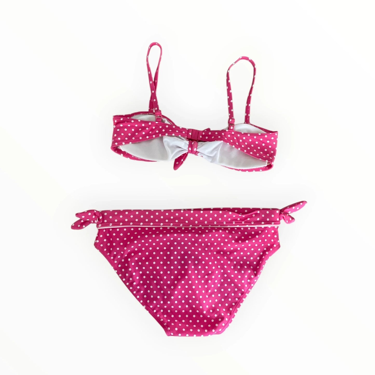 Pierrot Outlet roze bikini voor meisjes met wit stippenpatroon, strikdetails en verstelbare bandjes.