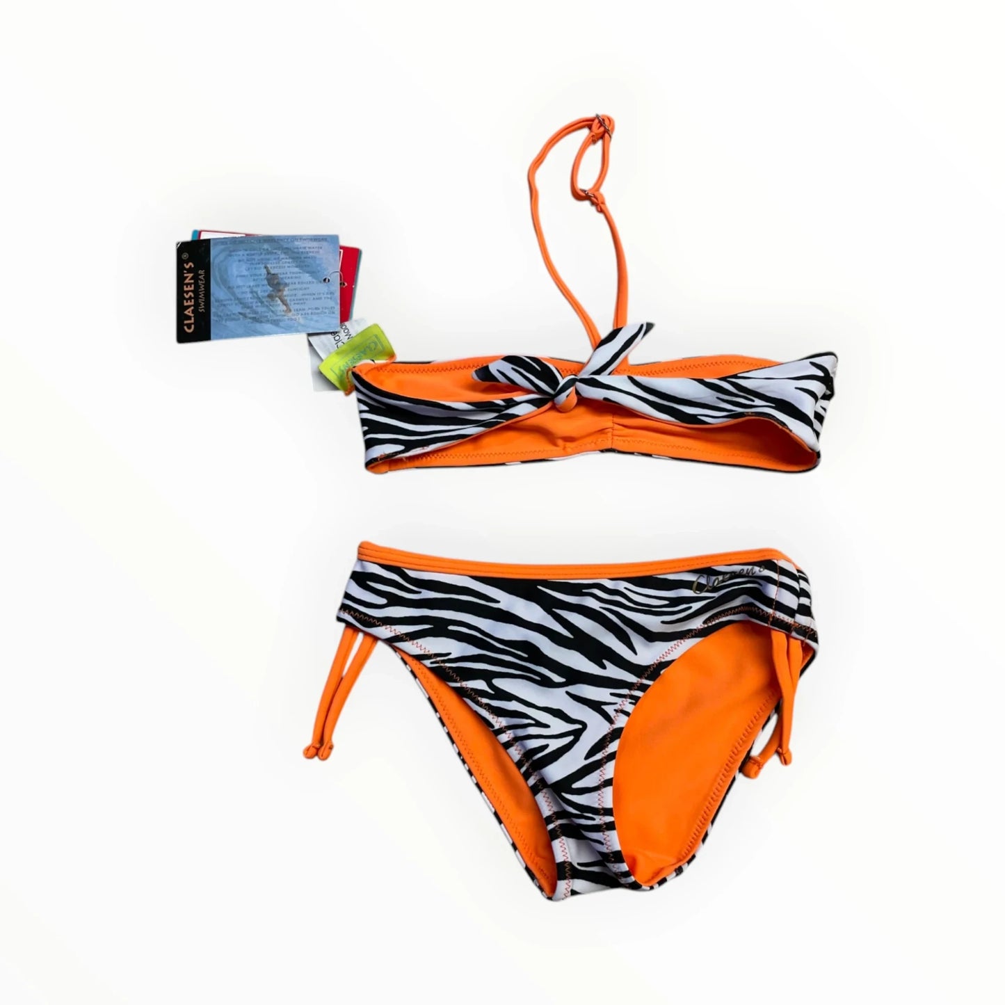 Pierrot Outlet meisjes bikini met zebraprint, oranje en zwart-wit. Bandeau top met strik en verstelbare bandjes. Broekje met strikjes aan de zijkant.