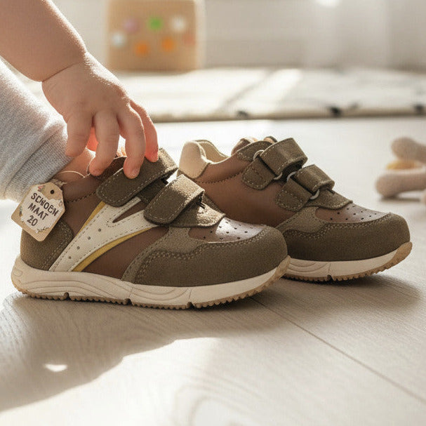 Pierrot Outlet kinderschoenen van bruin leer en suède met klittenband, gedragen door een kind in een lichte kamer.