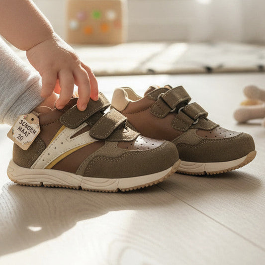 Pierrot Outlet kinderschoenen van bruin leer en suède met klittenband, gedragen door een kind in een lichte kamer.