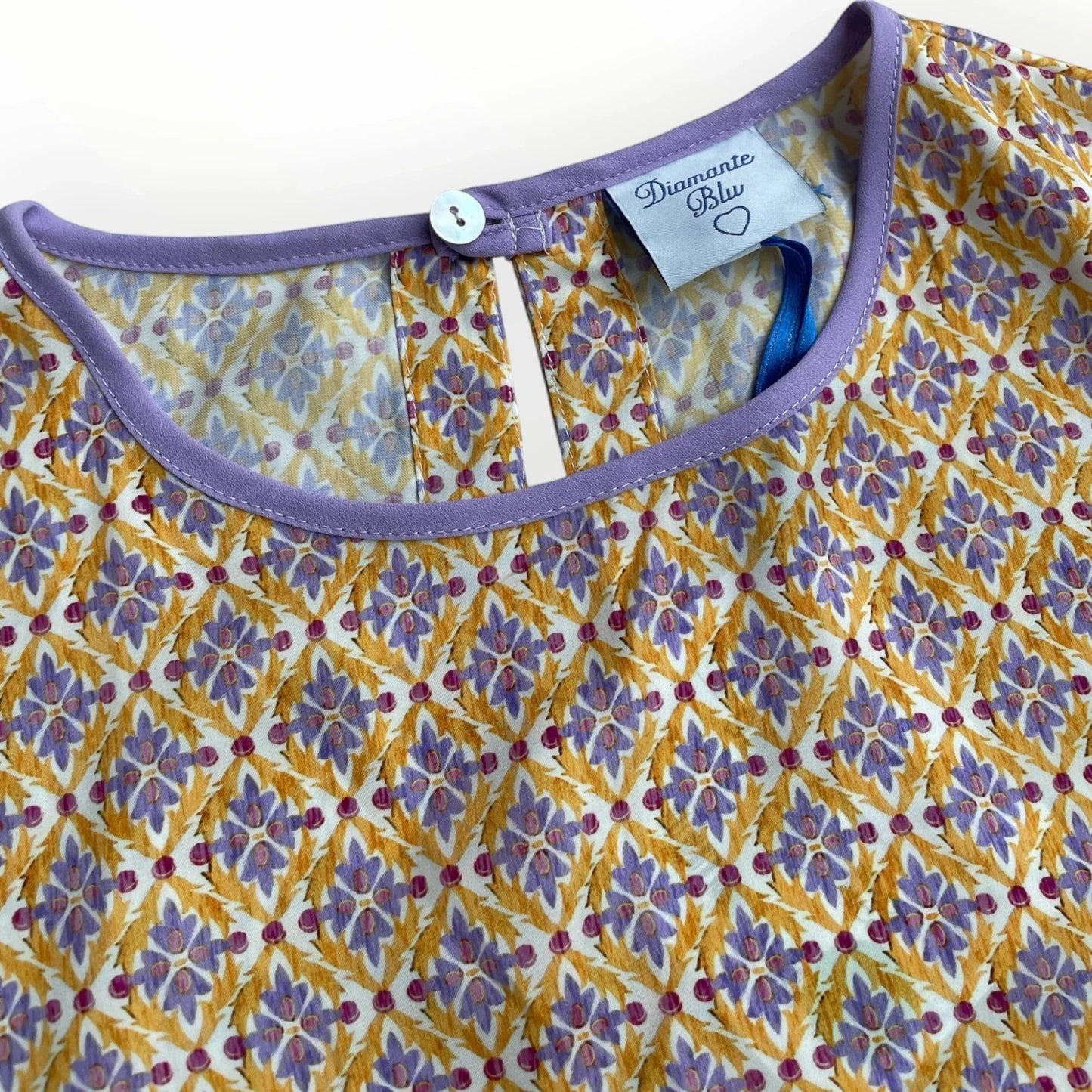 Pierrot Outlet dames blouse met paars en gouden bloemenpatroon, strikdetail en knoopsluiting aan de achterkant.