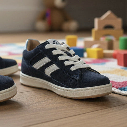 Pierrot Outlet donkerblauwe suède kindersneakers met witte veters en ritssluiting, gedragen met gestreepte sokken.