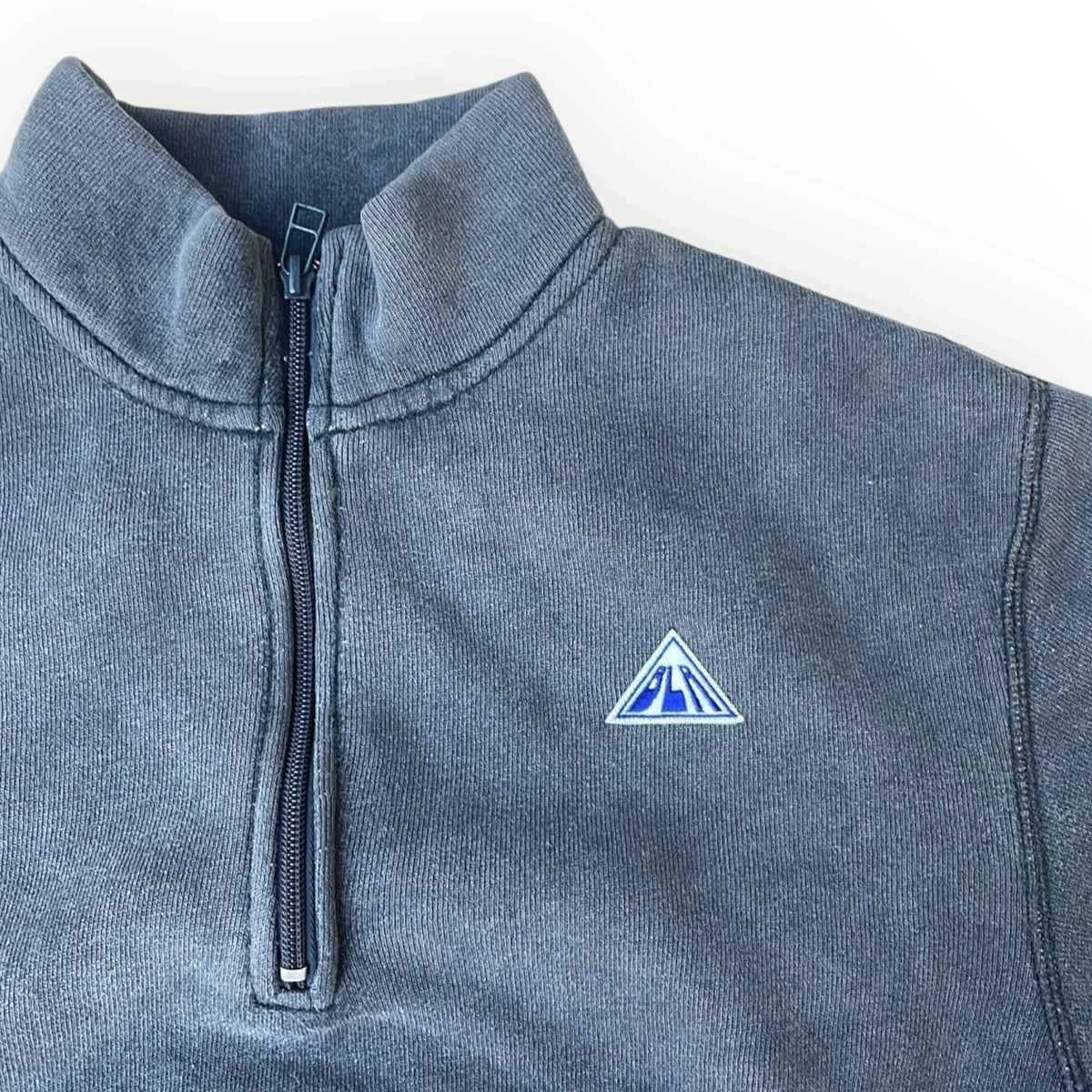 Pierrot Outlet donkerblauwe sweater met halve rits, opstaande kraag en geborduurde badge op de borst.