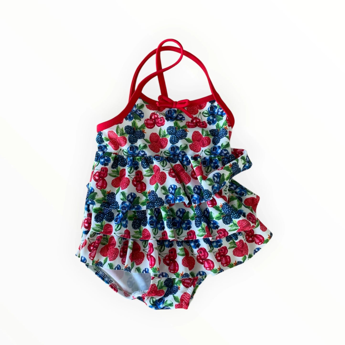 Pierrot Outlet gelaagd kinderzwempak met fruitmotief, ruches, rode bandjes en strikje voor een zomerse look.