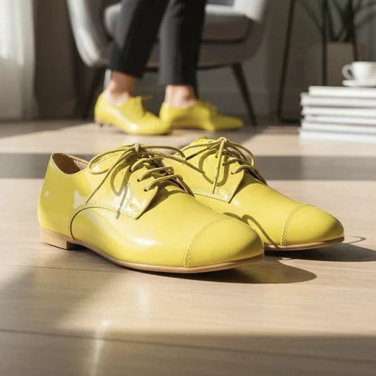 Pierrot Outlet gele lakleren veterschoenen in Oxford-stijl met platte zool, gedragen door een model in een woonkamer.