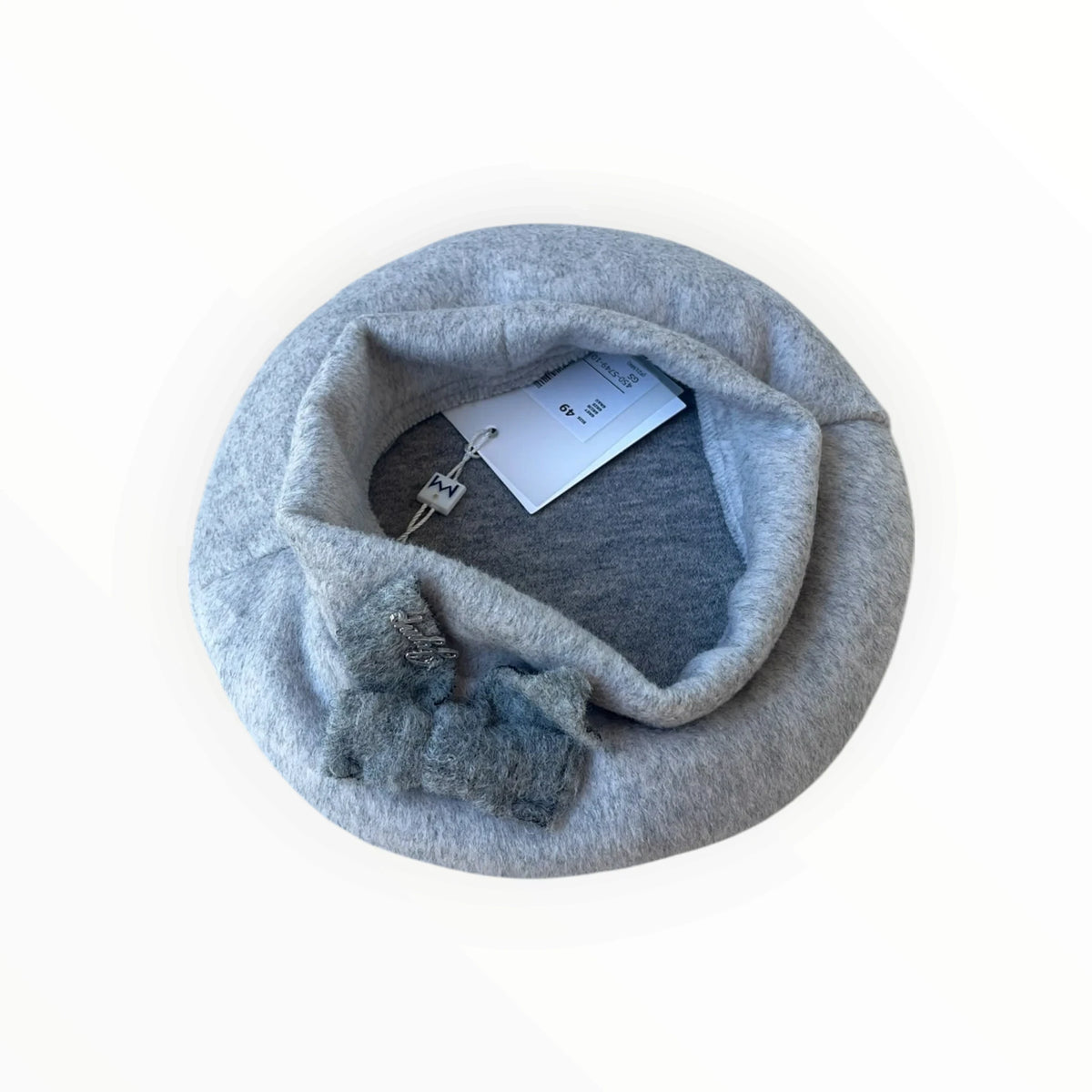 Pierrot Outlet grijze baret van zacht materiaal met een decoratieve strik en verfijnd metalen detail aan de voorzijde.