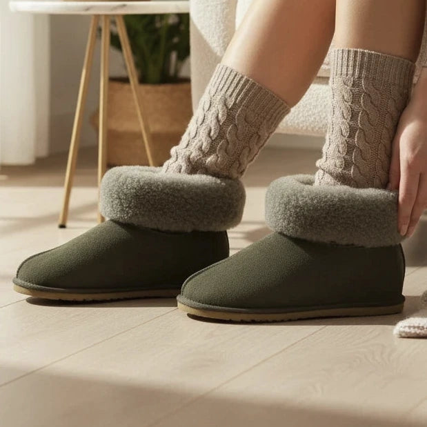 Pierrot Outlet grijze suède pantoffels met warme wolvoering en omgeslagen kraag gedragen in een gezellig interieur
