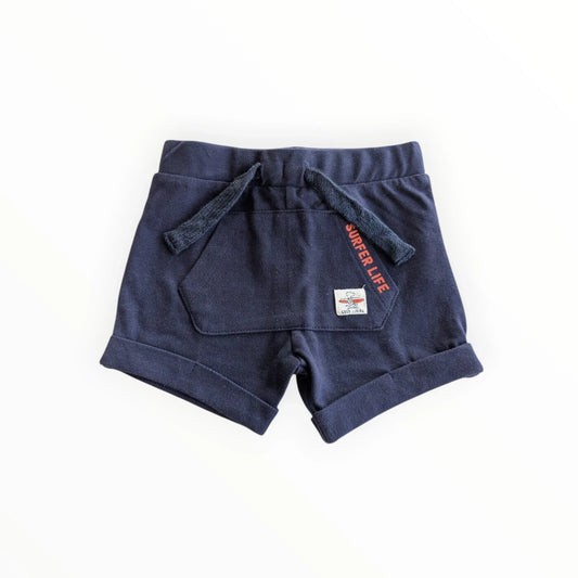 Pierrot Outlet navy blauwe katoenen jongens shorts met 'Surfer Life' print, trekkoord en opgerolde broekspijpen.