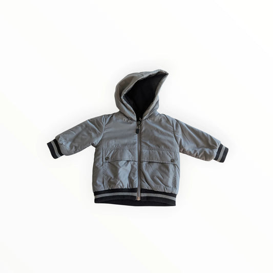 Pierrot Outlet grijze kinder winterjas met capuchon, ritssluiting, steekzakken en zwarte strepen op de boorden.