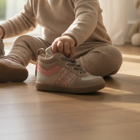 Pierrot Outlet kindersneakers van suède met roze glitterdetails en stevige zool, gedragen door een zittende baby.