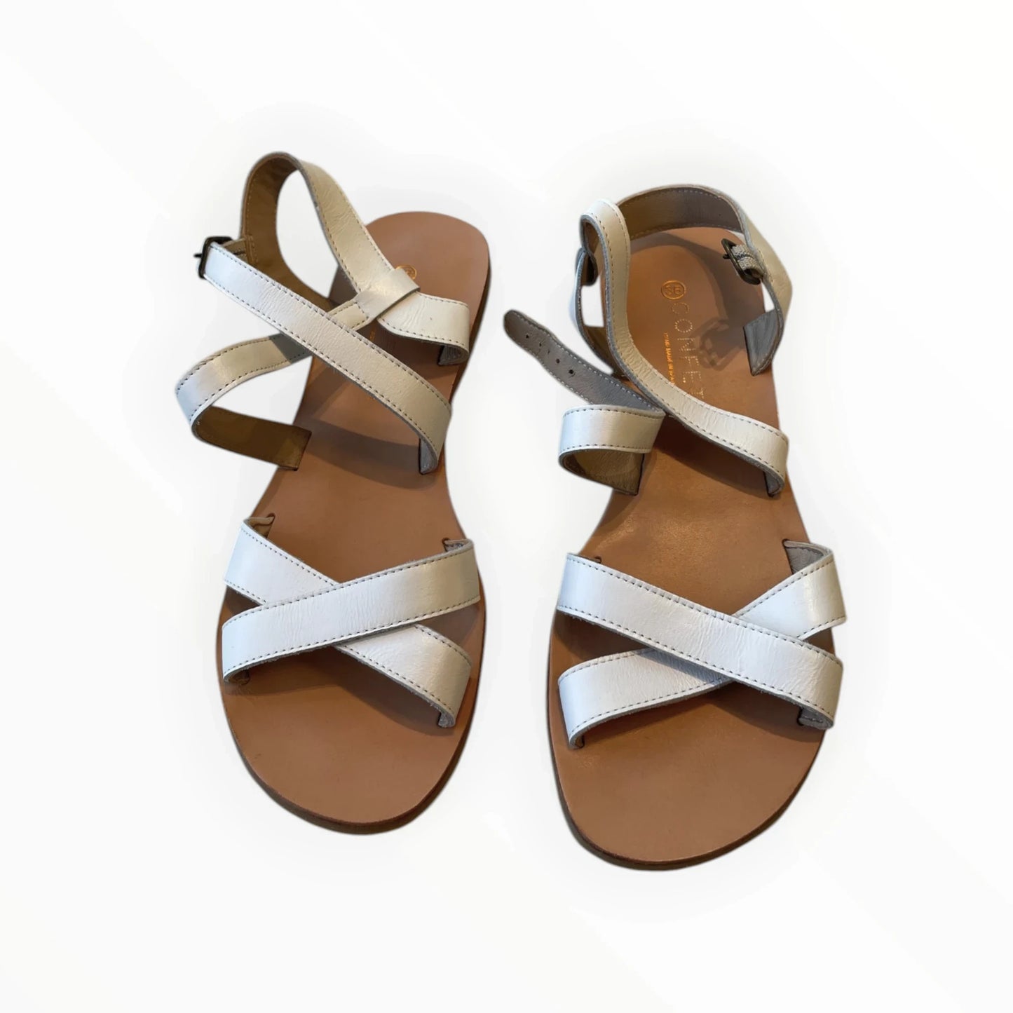 Pierrot Outlet crèmekleurige leren sandalen met gekruiste bandjes en gespsluiting aan de enkel.