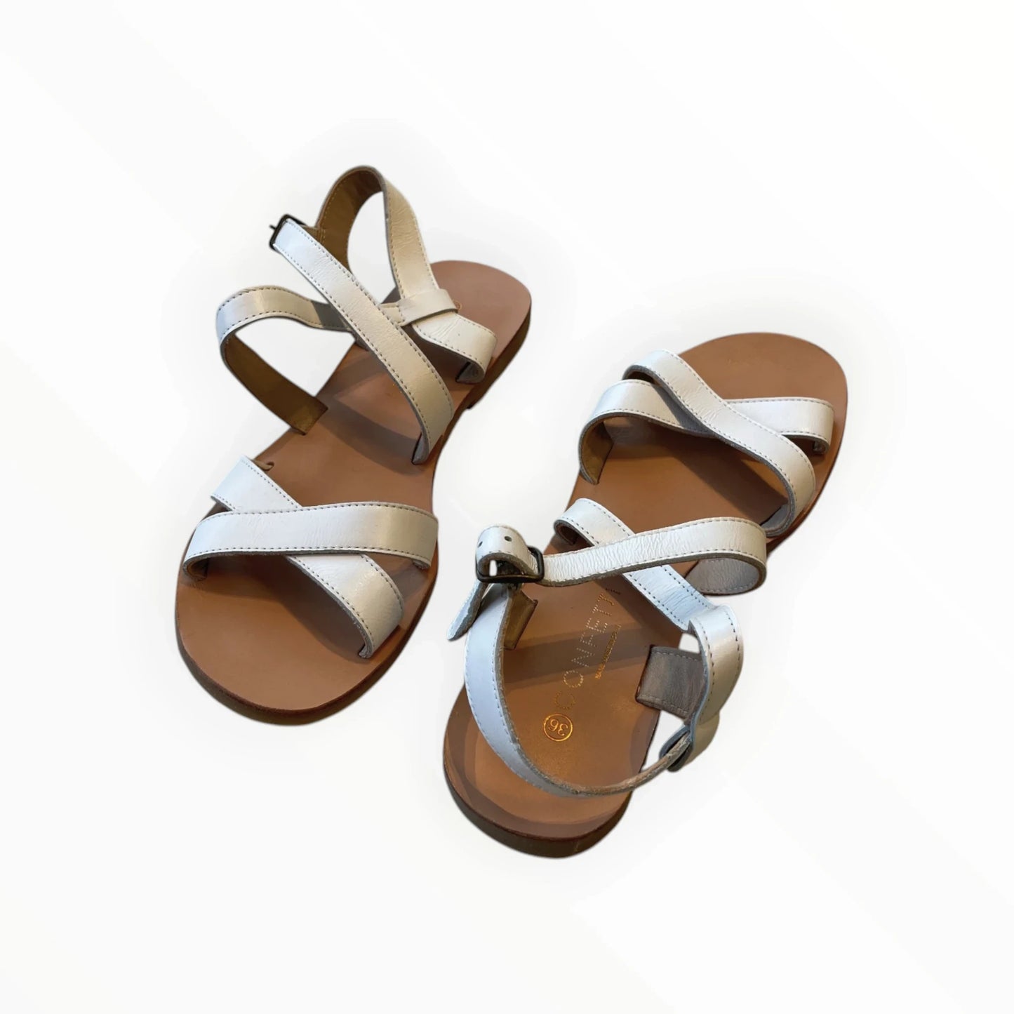 Pierrot Outlet crèmekleurige leren sandalen met gekruiste bandjes en gespsluiting. Platte zool voor comfort.