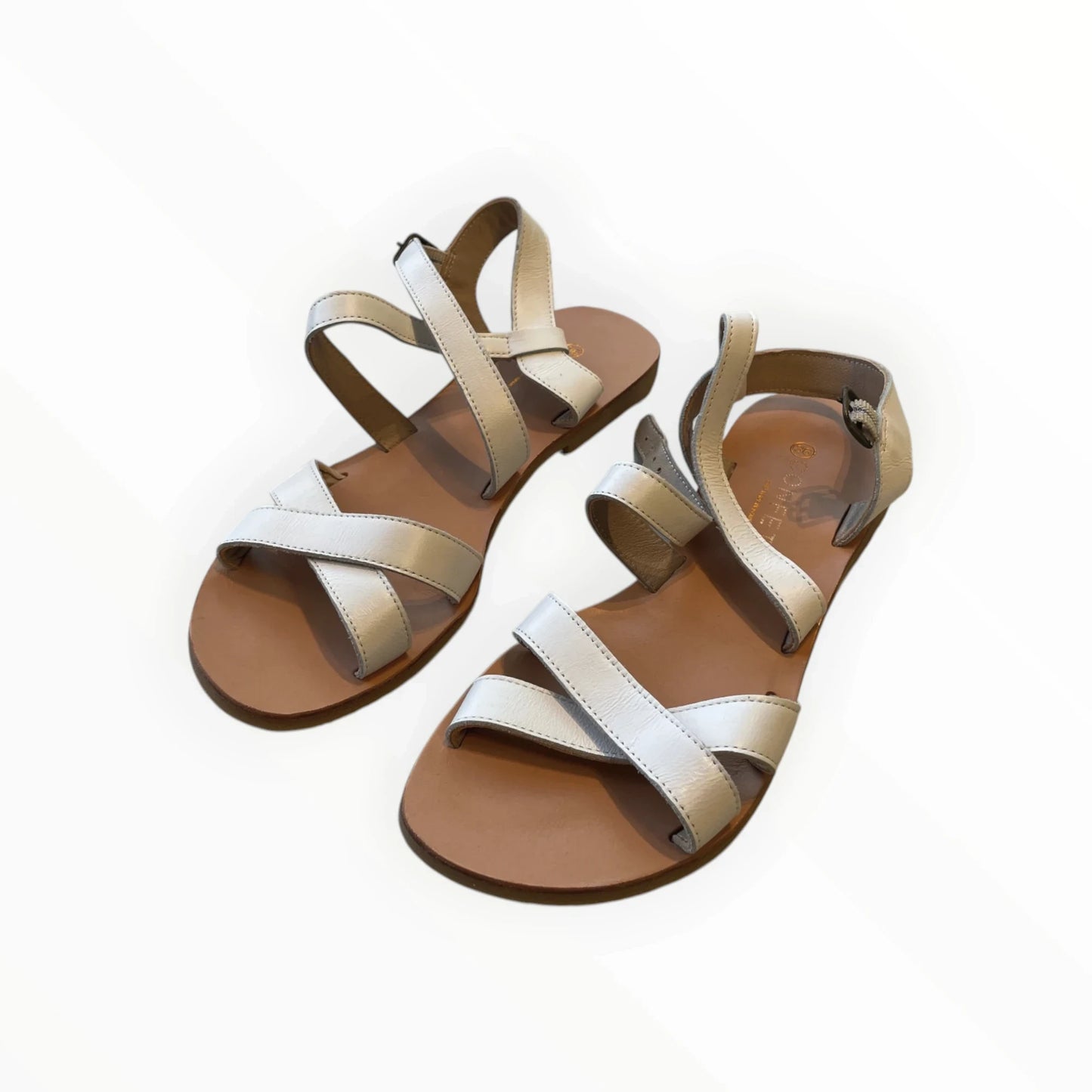 Pierrot Outlet crèmekleurige leren sandalen met bandjes en gespsluiting. Comfortabele platte zool.