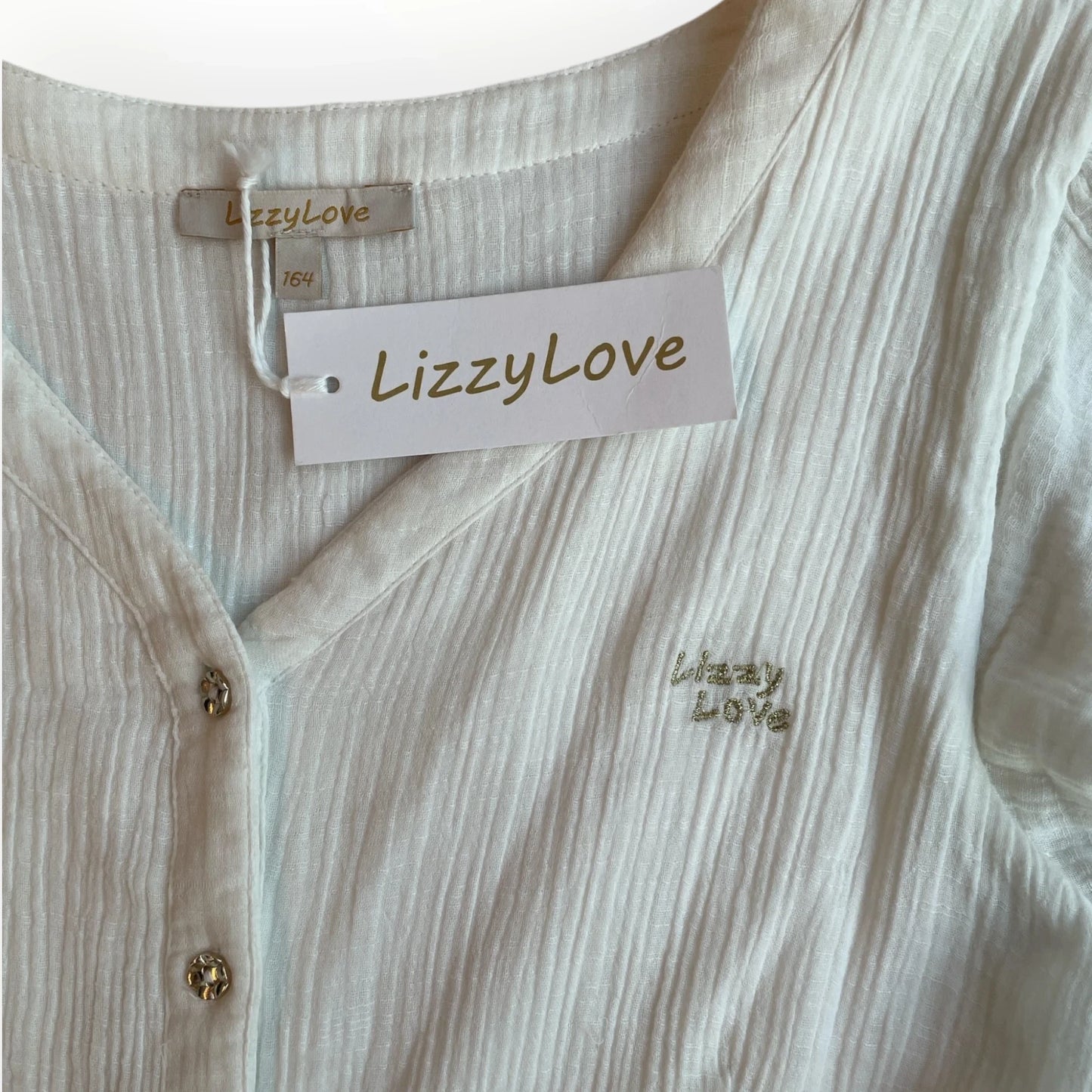 Witte LizzyLove meisjesjurk van Pierrot Outlet met V-hals, knoopsluiting en glinsterend logo op de borst.