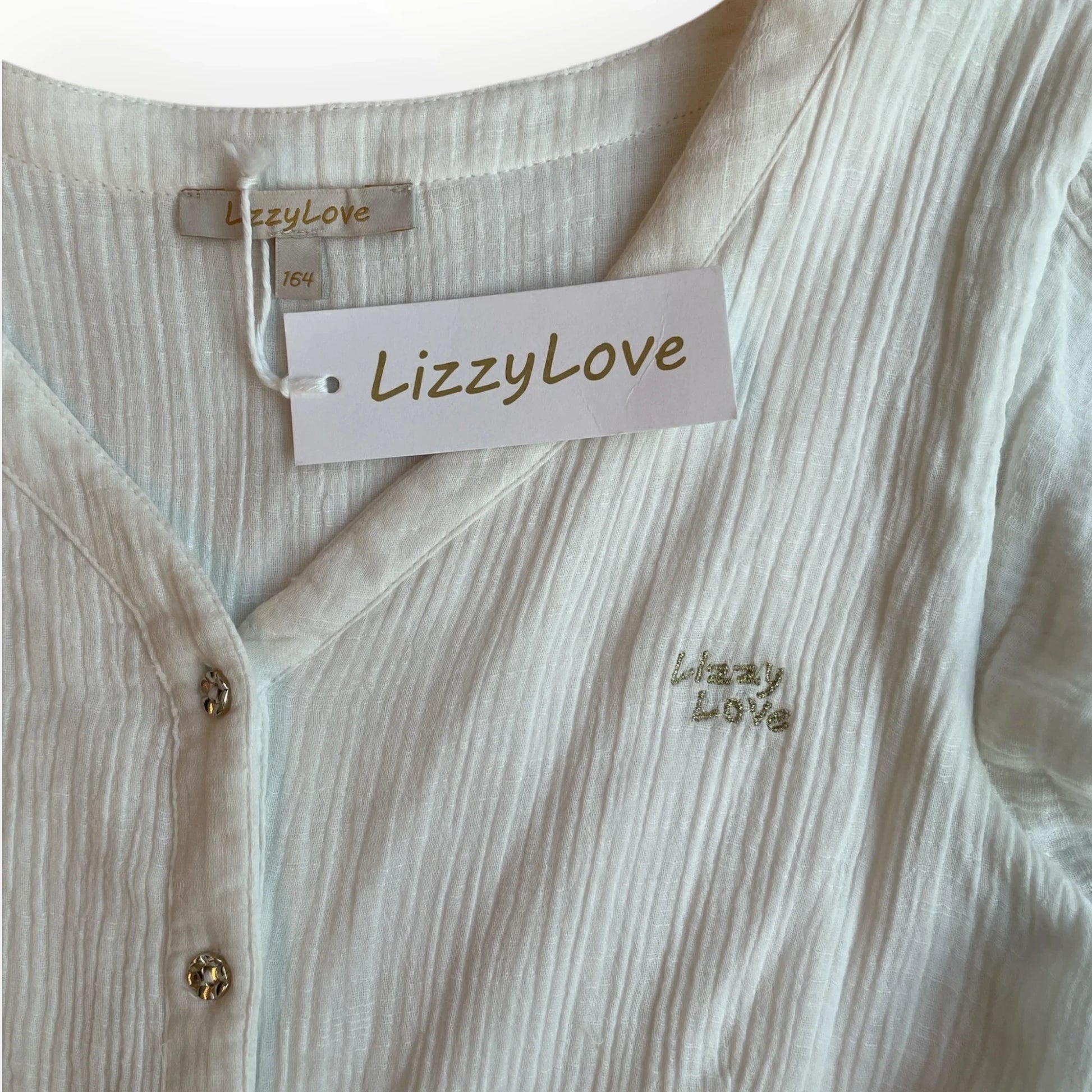 Witte LizzyLove meisjesjurk van Pierrot Outlet met V-hals, knoopsluiting en glinsterend logo op de borst.