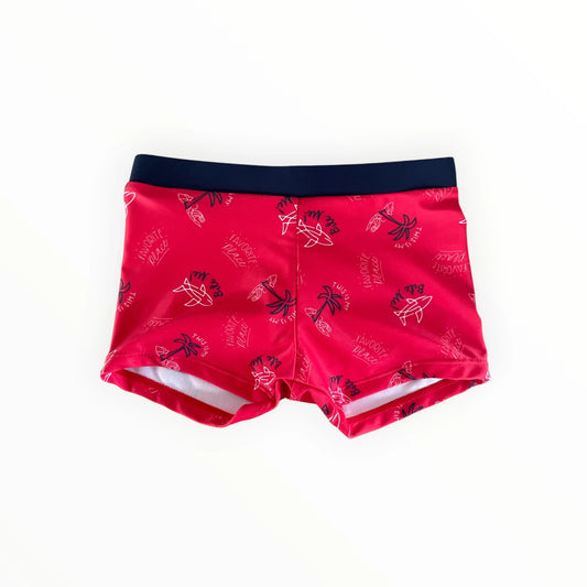 Pierrot Outlet rode zwemshort voor jongens met haaien- en palmbomenprint en donkerblauwe elastische tailleband.