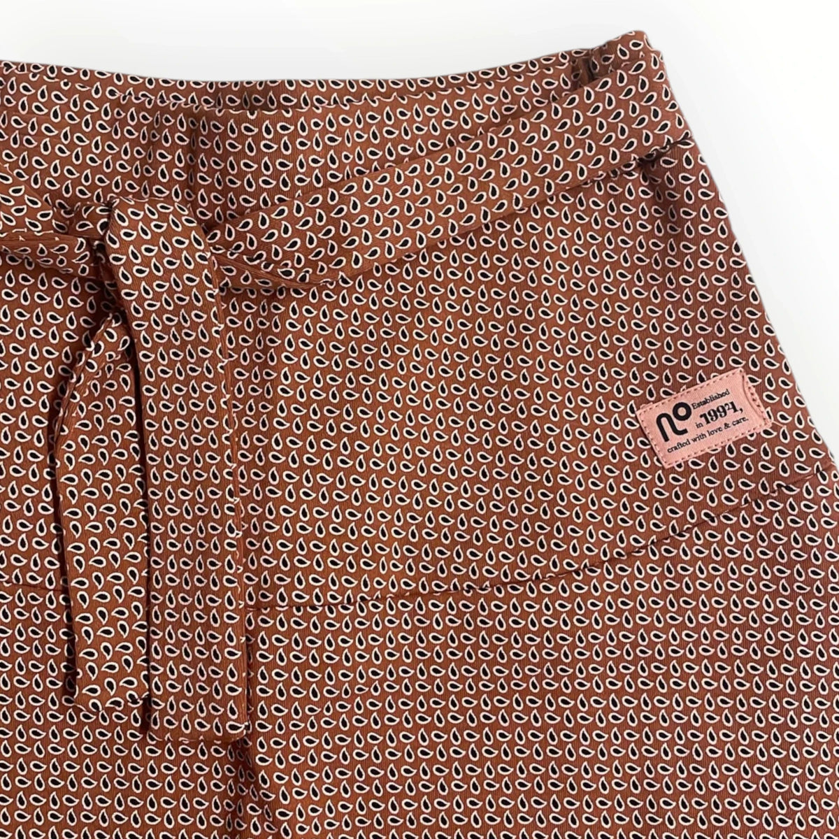 Pierrot Outlet roestbruine rok met strikceintuur en subtiel druppelpatroon en merklabel op de voorzijde