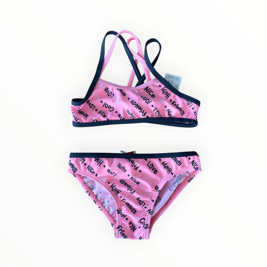Pierrot Outlet roze tweedelige bikini voor meisjes met tekstprint en donkerblauwe biezen en gekruiste bandjes.