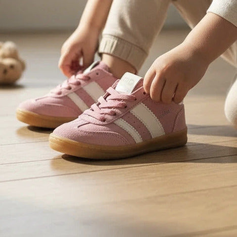 Kindje trekt roze suède Pinocchio sneakers van Pierrot Outlet aan met witte strepen en bruine rubberen zool
