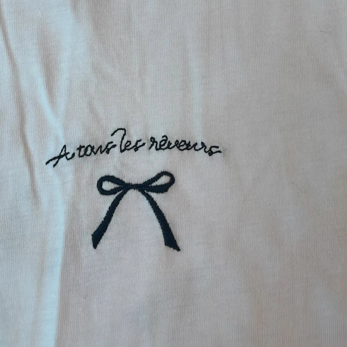 Pierrot Outlet wit katoenen T-shirt met zwart geborduurde tekst A tous les rêveurs en een elegant strikdetail